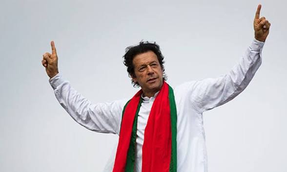 Imran Khan raising both index fingers at a rally, wearing a red and green scarf